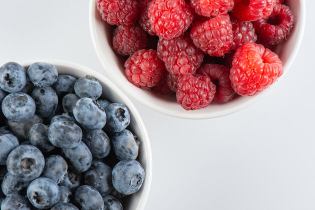 饮食新鲜的浆果 覆盆子和蓝莓在碗里 白色背景 俯视图配料宏蓝莓