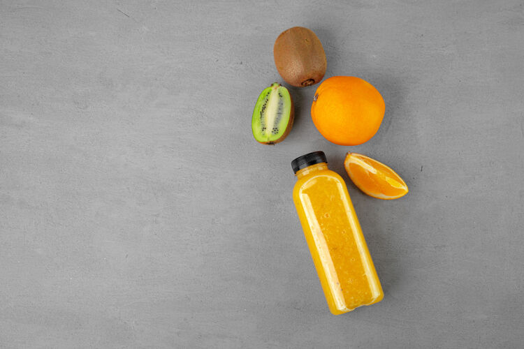 玻璃一瓶鲜榨橙汁放在灰色的表面上有机水果健康