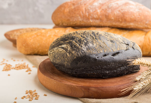 谷物不同种类的新鲜烤面包放在白色的木头表面法式面包小麦木板