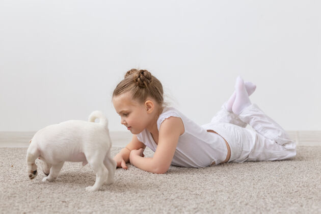享受人们儿童和宠物概念小女孩躺在地板上与可爱的小狗杰克罗素小朋友品种