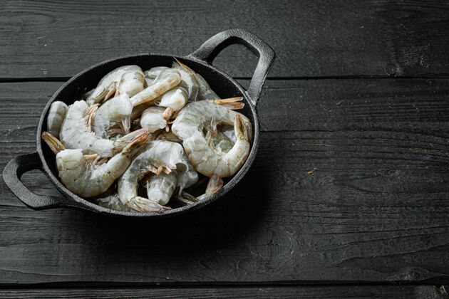 生的虎虾或亚洲虎虾 装在铸铁煎锅里 放在黑木桌上 有复印空间海鲜海洋大