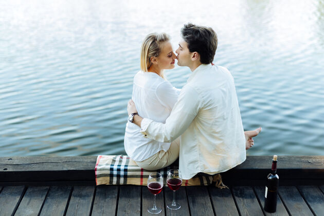 夫妻浪漫的感觉可爱的帅哥想亲吻他的妻子 而坐在河边与她传统木头婚礼