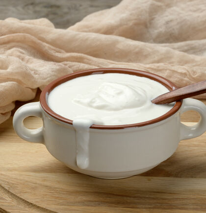 特写酸奶油放在一个棕色的陶瓷碗里 用木勺放在木板上 是发酵牛奶的有用产品餐桌食物膳食