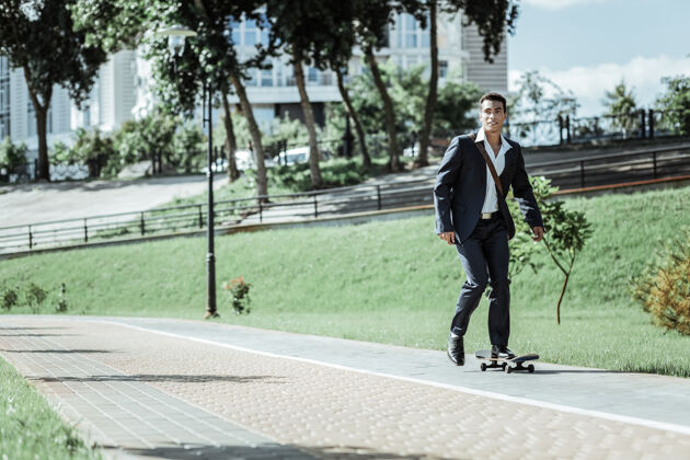 滑板每天训练活跃的男学生骑滑板和穿西装城市学生科技