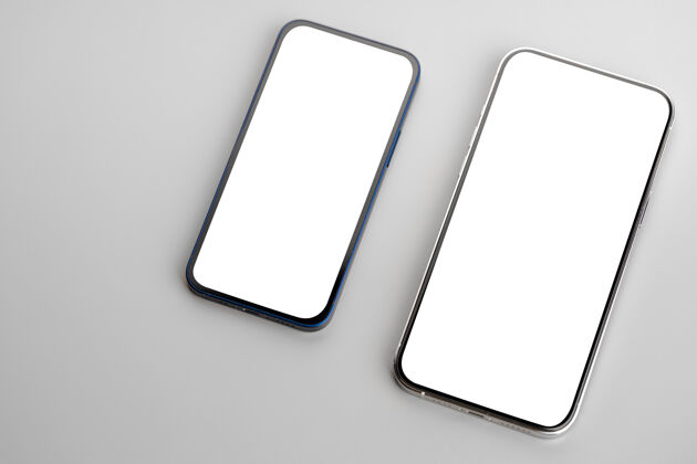 显示两个灰色表面上有白色空白屏幕的智能手机触摸空白屏幕