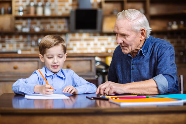 男人快乐的小男孩和他的爷爷一起画画 一起过周末桌子孙子祖父