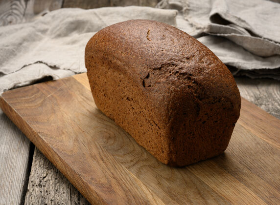 面包烤长方形黑麦面粉面包在棕色板上 健康食品健康小麦食品