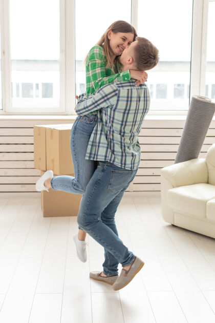 女人相爱的年轻夫妇抱着喜洋洋的搬家理念搬家公寓成人丈夫