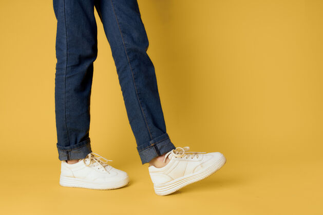 复制脚牛仔裤时尚鞋白色运动鞋黄色墙蓝时尚牛仔裤