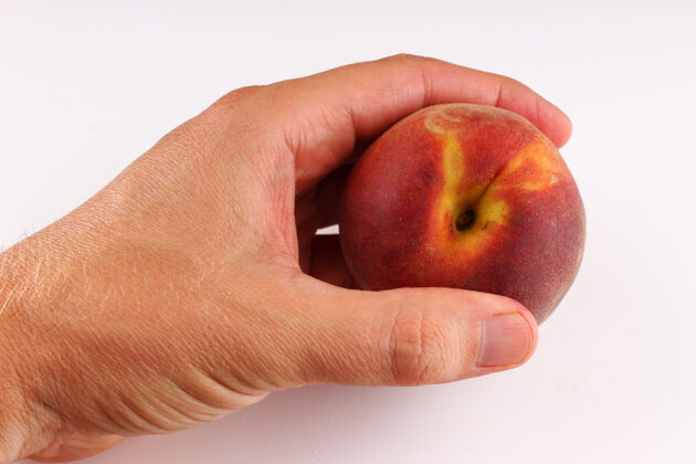 素食手拿桃子在白色的表面上水果片部分