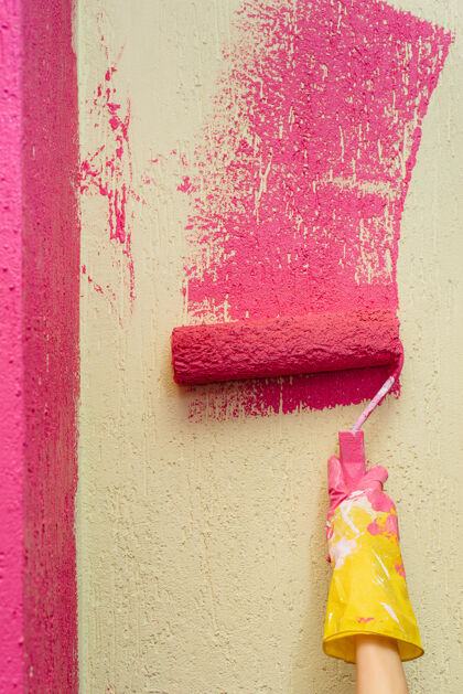 清洁特写镜头里的一个小女孩把一堵黄色的墙漆成了粉红色修理内部工人油漆工重建