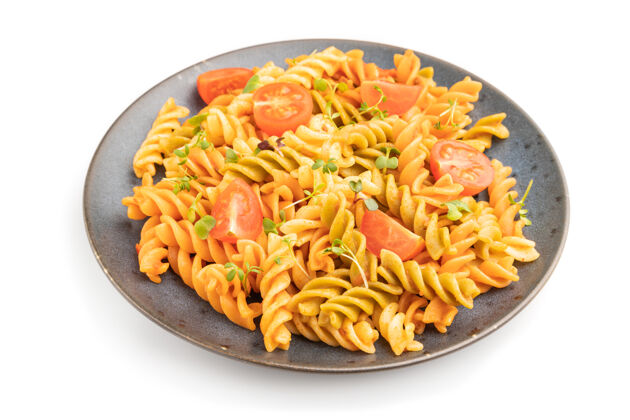 传统Tortiglioni粗面粉面食 白色表面有番茄和微绿芽食物切片健康