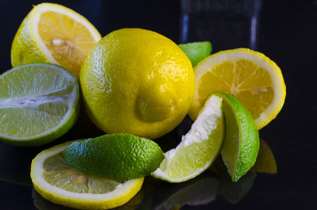 配料新鲜的青柠和柠檬放在黑色的表面上路径自然健康