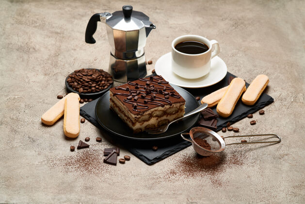 饼干一份传统的意大利提拉米苏甜点和摩卡咖啡机放在灰色的水泥桌上甜点无人石头