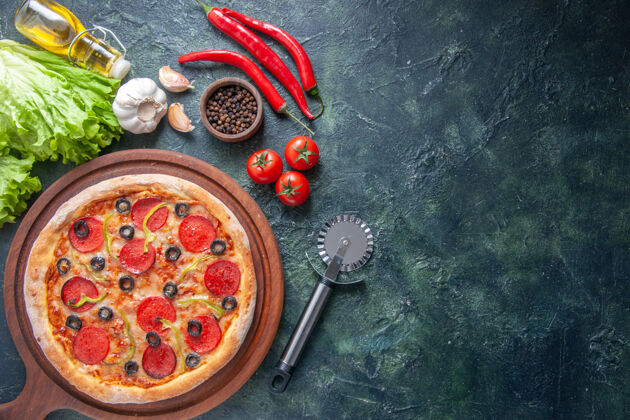 大蒜美味的自制披萨放在木制砧板上番茄番茄酱大蒜素胡椒油瓶绿色的包在黑暗的表面瓶子晚餐奶酪