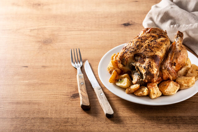 食物自制烤鸡配土豆放在木桌上餐桌晚餐盘子