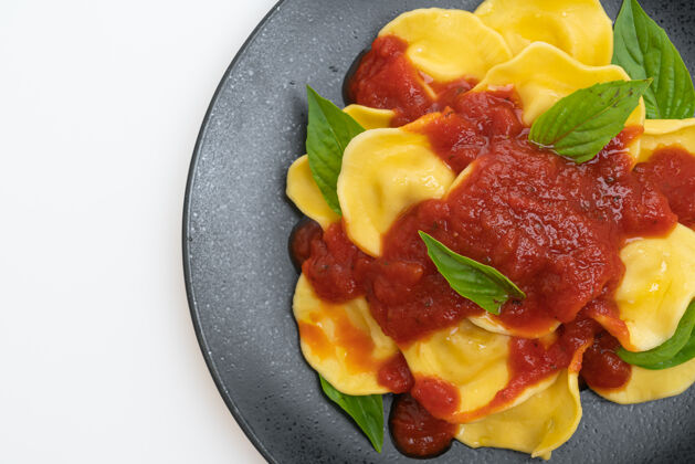 盘子白桌子上的西红柿汁罗勒馄饨素食主义者广场奶酪