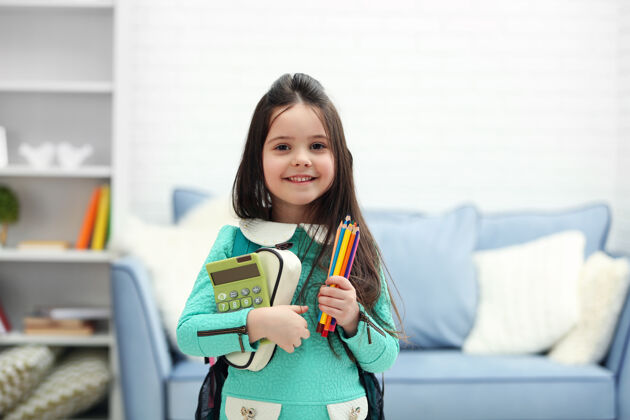童年小女孩背着绿色的背包 在客厅里拿着文具和计算器房间手年级