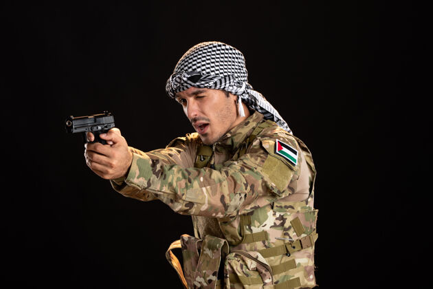 人巴勒斯坦士兵用枪瞄准黑墙男性制服伪装