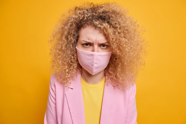疾病限制病毒传播的风险不高兴的妇女穿着正式的衣服戴防护面具 以防止冠状病毒需要病毒疫苗隔离过黄墙流行病爆发检疫室内卷发病毒