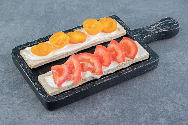 早餐在木板上用西红柿烤脆面包切片饮食谷类