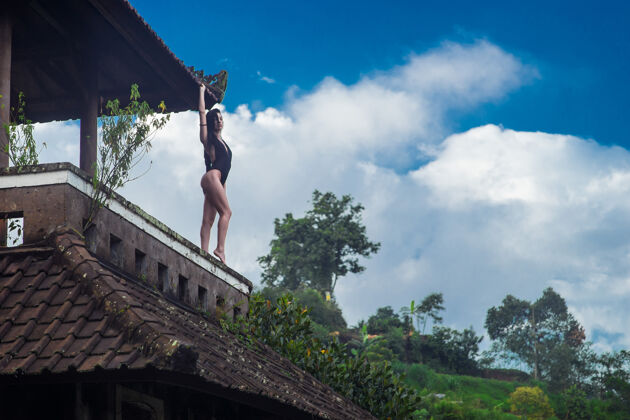 可爱穿着泳装的女孩在巴厘岛一家神秘的废弃烂旅馆的屋顶上 穿着蓝色的衣服天空与蓝天泳装白天绿色