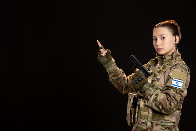 黑色身穿迷彩服的女兵在黑墙上持枪制服战士性感