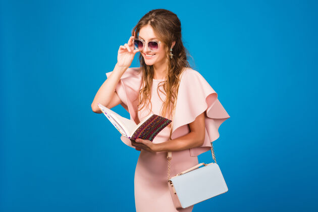 女士穿着粉色奢华连衣裙的年轻时尚女人在看书快乐衣服时尚