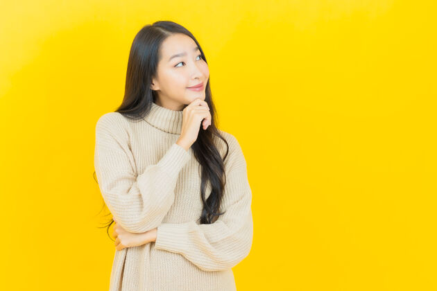 时尚美丽的亚洲年轻女子在黄色的墙上微笑明亮生动充满活力