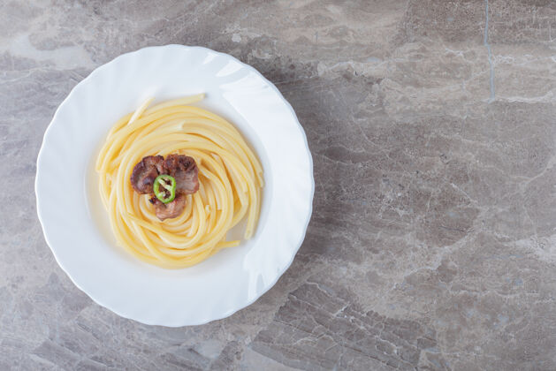 意大利面把烤好的肉放在意大利面上 放在盘子里 放在大理石的表面上美味美味料理