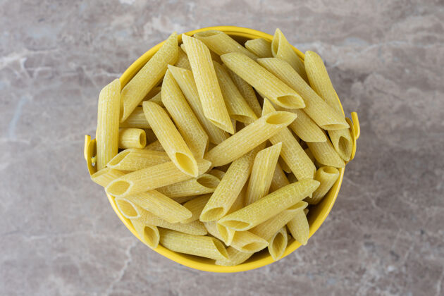碳水化合物黄色桶里的意大利面 放在大理石表面上风味美味美味