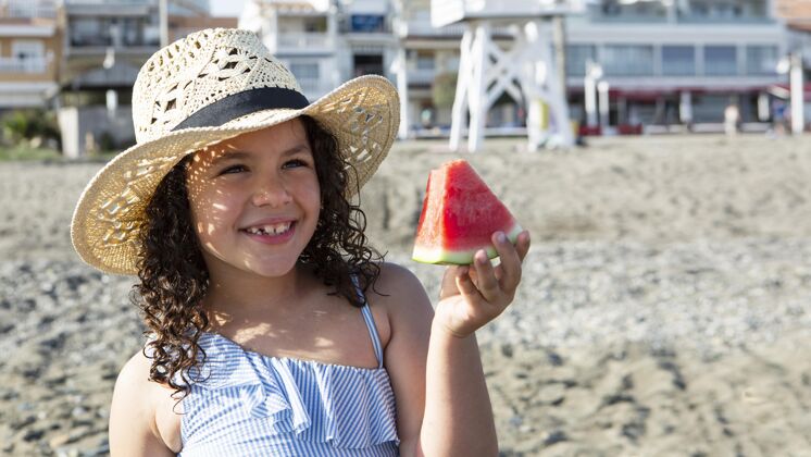 海滩特写笑脸女孩拿着西瓜片家庭乐趣假期