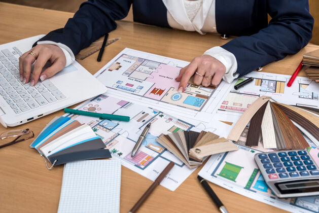 计划设计师在办公室里工作 拿着颜色样本 笔记本电脑和建筑平面图调色板素描蓝图