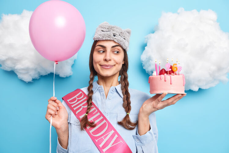 正面女人在家里庆祝26岁生日手捧喜庆蛋糕充气氦气球穿丝带衬衫准备派对蓝色隔离女人女性氦