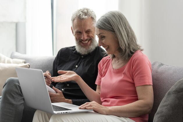 养老金老两口在家沙发上用笔记本电脑设备妻子老人