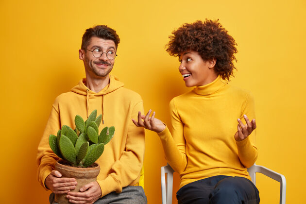 男人女人积极地做手势 和丈夫讨论一些事情 试图解释她的想法 搬进新公寓 在黄色的椅子上摆姿势手势乐观运动衫