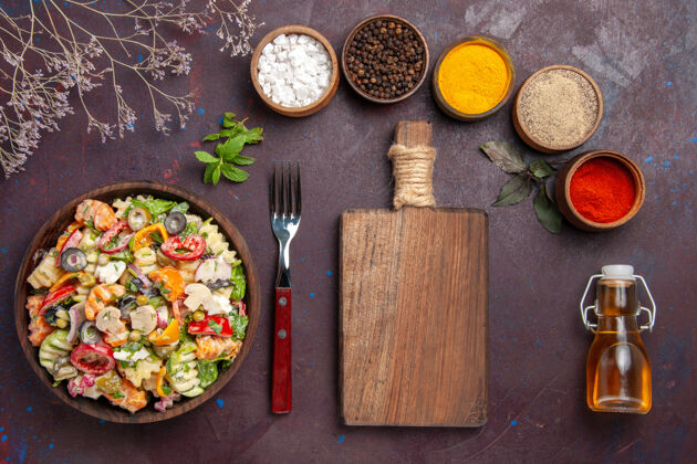 顶部俯瞰美味的蔬菜沙拉搭配不同调味料的深色背景健康蔬菜沙拉减肥午餐沙拉饮食晚餐