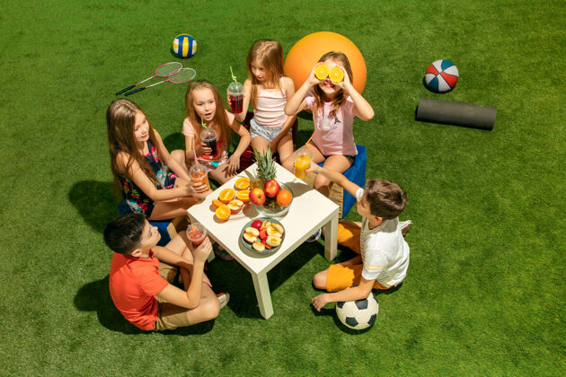 年轻儿童时尚概念一群十几岁的男孩和女孩坐在公园的绿色草地上儿童多彩的衣服 生活方式 流行的色彩概念男孩童年行动