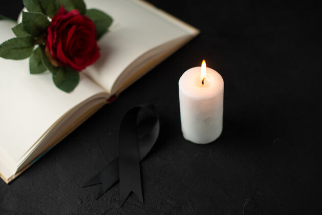 葬礼打开的书和蜡烛上的黑玫瑰的正面视图蜡烛红玫瑰光
