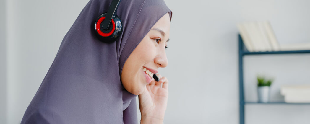 商务妇女亚洲女士戴着耳机看网络研讨会听在线课程在家里通过电话会议视频沟通阿拉伯语会议战略