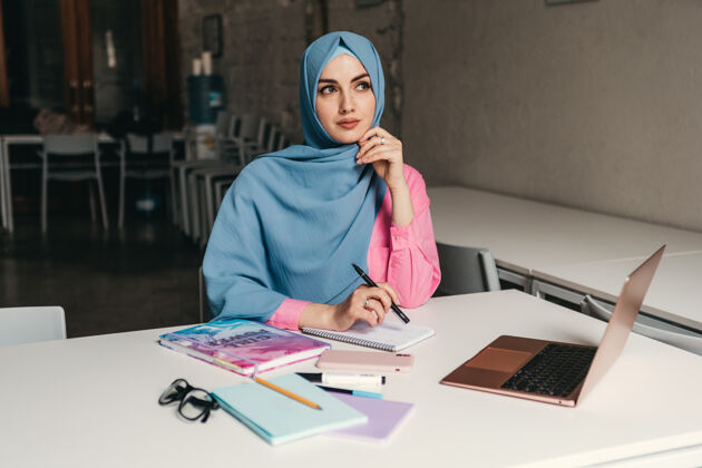 传统年轻漂亮的现代妇女戴着头巾在办公室的笔记本电脑上工作 教育在线女商人办公桌多元化