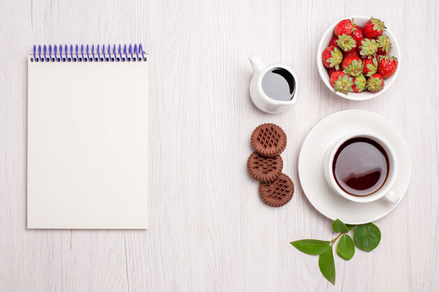 草莓俯瞰一杯茶 白色桌面上放着饼干和草莓糖茶饼干甜饼干热的潘趣酒饼干