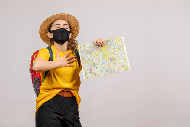 面罩前视图：背着背包的年轻女子举着地图 手放在胸前灰色手旅游
