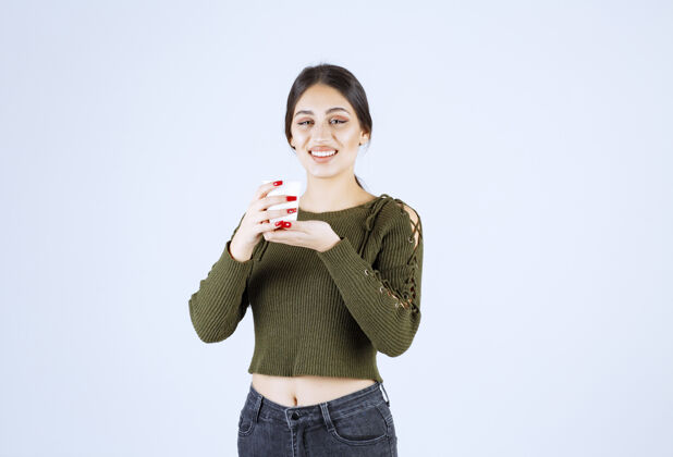 成人在白色背景上 年轻的黑发女人高高兴兴地拿着塑料杯年轻持有女性