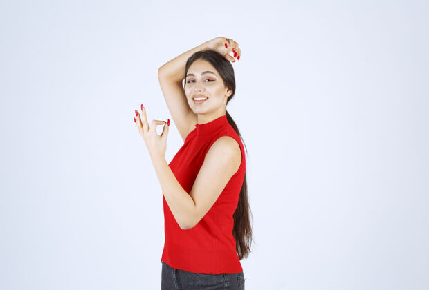 人穿红衬衫的女孩显示出积极的手势满意工人喜欢