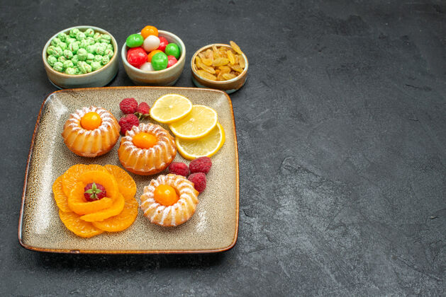 派前视美味的小蛋糕 柠檬片 橘子和糖果 放在深色的桌子上 茶 水果 饼干 甜甜的饼干派桌子前面水果