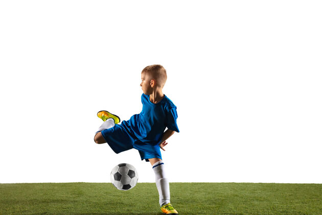 球员穿着运动服的足球或足球运动员的小男孩在白色工作室背景上用球假装或踢进球适合在比赛中扮演男孩的动作 动作 动作制服比赛草地