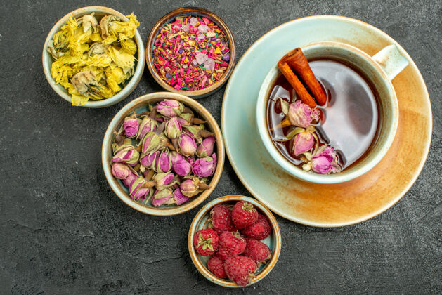 风味顶视图一杯茶 以花儿和覆盆子为深色背景 茶果饮花香膳食茶胡椒