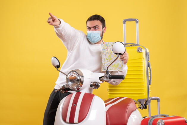 地图旅行概念的俯视图 戴着医用面罩的年轻人站在黄色手提箱的摩托车旁男人摩托车旅行