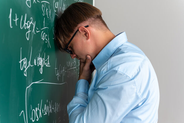 公式戴着眼镜的年轻男老师站在教室里数学公式的黑板旁 神情茫然 没有答案拼图数学教室